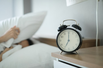Woman sleep on the bed turns off the alarm clock wake up at the morning, Selective focus.