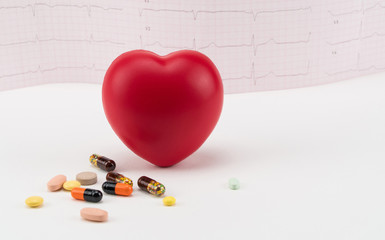 Toy heart with pills on electrocardiogram background. Concept healthcare. Cardiology - care of the heart