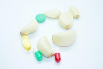 Garlic cloves and tablets located on a white background