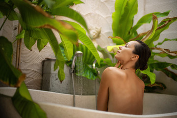 Woman relaxing in outdoor bath with tropical leaves at Bali