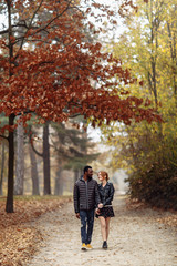 Fototapeta na wymiar Happy interracial couple walking in autumn park