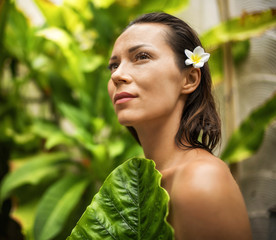 Woman relaxing in outdoor bath with tropical leaves at Bali