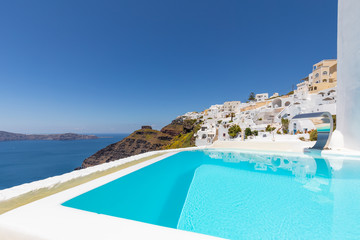  View of caldera and swimming pool in foreground, typical white architecture of Imerovigli village on Santorini island, Greece 