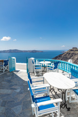Fototapeta na wymiar Santorini island. Romantic white chairs on white caldera with sea view. Luxury travel and vacation destination. Amazing summer landscape, sea view. Perfect tourism poster template, copyspace 