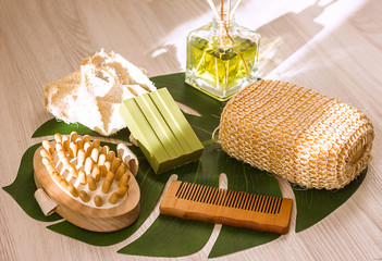 natural ecological washcloth, wooden brush for dry massage, olive soap and wooden comb on a wooden light background, top view, concept of ecology and body care with natural products