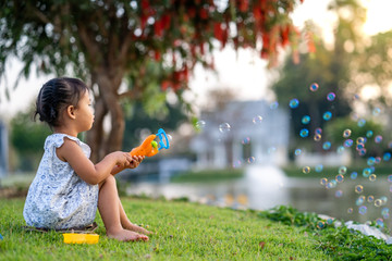 Cute little girl playing with soap bubbles at park.