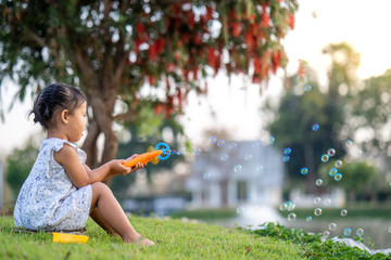 little girl playing with soap bubbles along the lake.