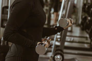 sport, fitness, bodybuilding, weightlifting and people concept - close up of woman flexing arms with dumbbell in gym.