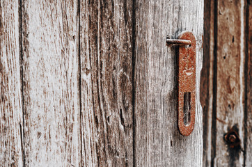 Old rusty deadbolt handle on a weathered wooden door