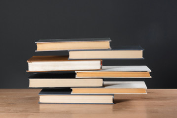 Stack of books on the school desk over blackboard background.