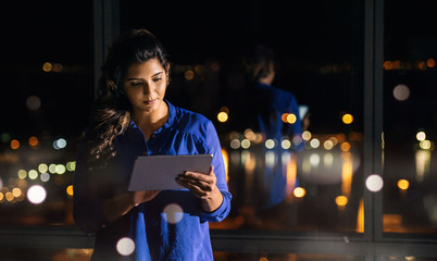 Young businesswoman working late with a tablet in an office