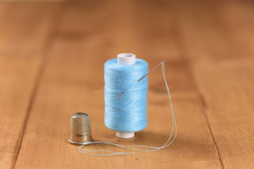 White blue cotton thread bobbin with needle close up