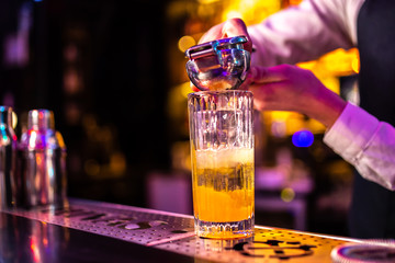 Close-up of expert bartender making cocktail in bar.