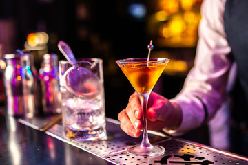 Expert bartender serves cocktails at the bar