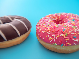 chocolate and strawberry pink donuts lie on a blue background close up