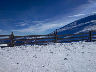 View of the nature during winter season with snow covering the ground and mountain in the background and wooden fence