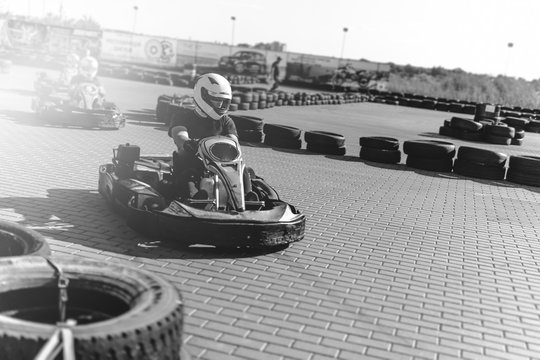 Black and white. A driver in gear and helmet drives a racing car. In action. Go karts racing, sreet karting, rent. extreme sport. fun entertainment for drivers