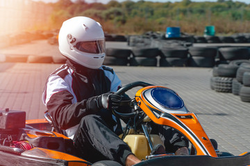 A driver in gear and helmet drives a racing car. In action. Go karts racing, sreet karting, rent. extreme sport. fun entertainment for drivers. Soft light glow, copy space