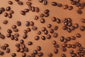 Coffee beans on a brown colored background. Top view. Place for text.