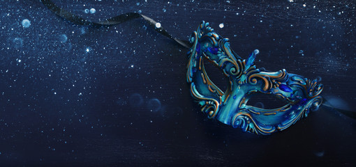 Photo of elegant and delicate blue Venetian mask over dark wooden background