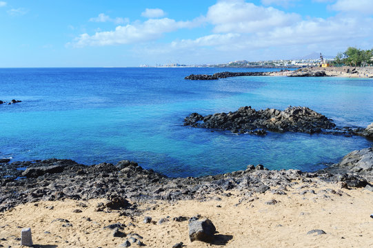 Lagoon with turquoise clear water in Playa Jablillo beach, in Costa Teguise, Lanzarote, Canary islands. Sandy beach with blue sea, volcanic rocks
