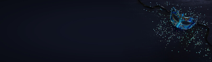 Photo of elegant and delicate blue Venetian mask over dark wooden background