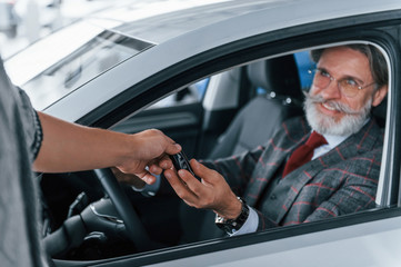 Modern stylish senior man with grey hair and mustache is in the modern car