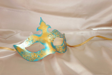 Photo of elegant and delicate gold Venetian mask over white silk background