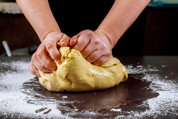 Woman kneading dough for making donuts.