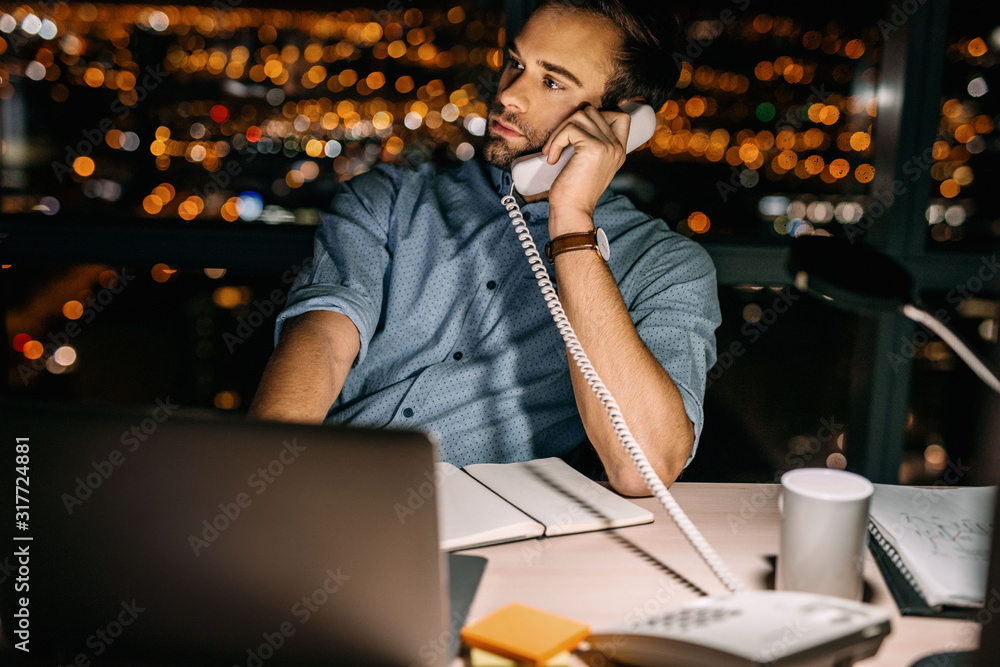 Wall mural businessman working overtime at his office desk overlooking the city