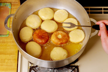 Frying and flipping round donuts in hot oil.