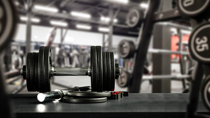 Fototapeta na wymiar Black desk of free space for your decoration and blurred gym interior.Metal dumbbells and fit life 