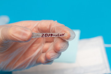 doctor's hand in a surgical glove with a test tube with the inscription 2019-nCoV. Novel coronavirus 2020