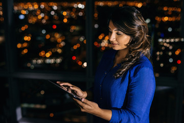 Young businesswoman working on a tablet late in the office