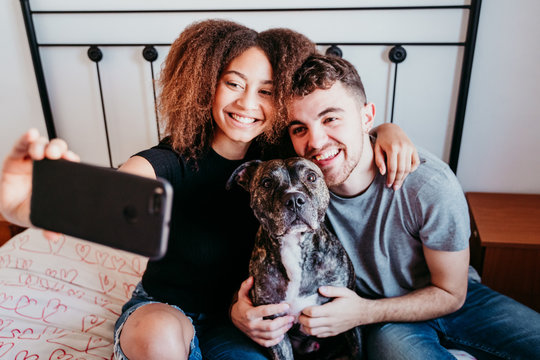 happy couple in love at home. Afro american woman, caucasian man and their pit bull dog together. Family concept