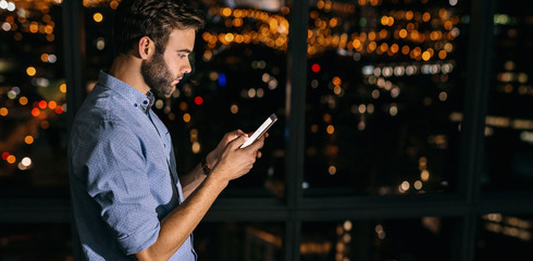 Young businessman working late at night reading text messages