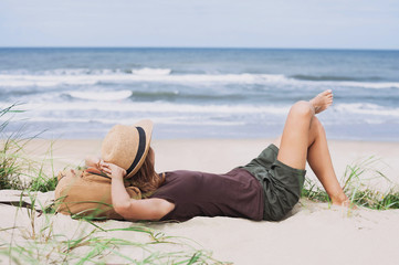 Young woman resting by the sea. Girl lying down on the beach. Enjoying life, summer lifestyle, relaxation and travel concept