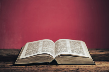 Open bible on a old oak wooden table. Beautiful green wall background.