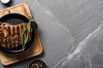 fried steak in pan on gray marble table top view