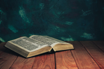 Open bible on a red wooden table. Beautiful green wall background.