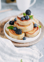 Russian fritters with blueberries, blackberries and bananas and honey on top