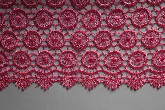 Edge of bright pink crochet lace on neutral background