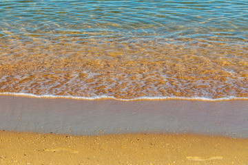 Texture with clear sea water and a fragment of a sandy beach