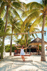 A girl riding on a swing on a sunny day. Kuredu Tourist Island, Republic of Maldives