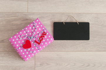 Valentine's day background. Cute composition with handmade gift boxes and red hearts on wooden table. Happy birthday or anniversary congratulation.