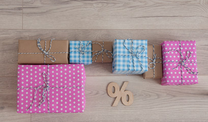 percentage sign and colorful gift box on wooden floor indoors background.