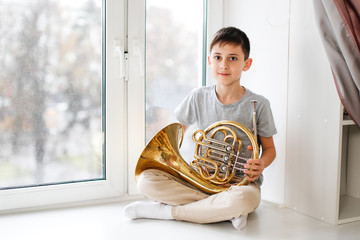 Caucasian boy learns to play horns, light window
