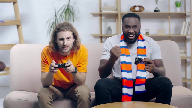 happy african american man playing video game with friend 