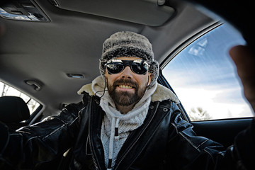 driver of the car in winter clothes, man behind the wheel, a winter journey on car,  brutal man with  beard on the car,  professional traveler