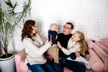 Cheerful family at home sitting in sofa. Parental love, upbringing and care. brother and sister...